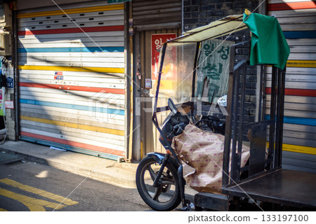 A parked motorized rickshaw on a narrow street with closed shops in Myeongdong shopping district in Seoul, South Korea 133197100