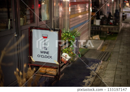 Street scene at night with a sign reading It's Wine O'Clock next to a bar entrance in Seoul, South Korea 133197147