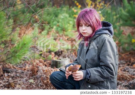 Girl with pink hair finding mushroom in forest 133197238