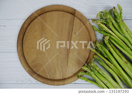 Bunch of fresh green asparagus stems with cutting wooden board on wooden background Bunch of fresh green asparagus stems with cutting wooden board on wooden background 133197293