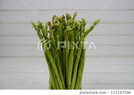 Bunch of fresh green asparagus stems on wooden background Bunch of fresh green asparagus stems on wooden background 133197296