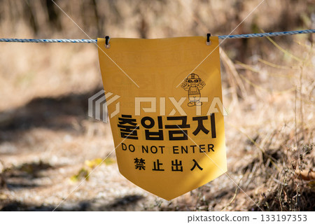 Yellow warning sign with Korean and English text Do Not Enter hanging on a rope outdoors in Seoul, South Korea 133197353
