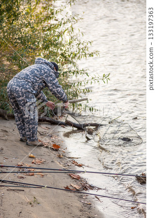 Man in camouflage clothing holding a fishing net on a riverbank of Han river in Seoul, South Korea 133197363