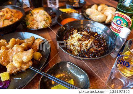Assorted Asian dishes and Chinese food on a wooden table with drinks at a restaurant in Chinatown in Incheon, South Korea 133197365
