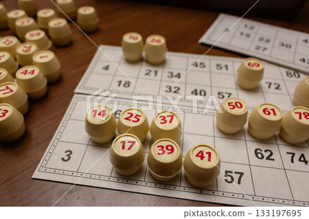 Playing lotto game. Cubes with figure on bingo card background. Nostalgia lifestyle. Table games. Retro games. Barrel with number and paper cards for bingo game. Holiday leisure. Luck concept. Playing lotto game. Cubes with figure on bingo card background. Nostalgia lifestyle. Table games. Retro games. Barrel with number and paper cards for bingo game. Holiday leisure. Luck concept. 133197695