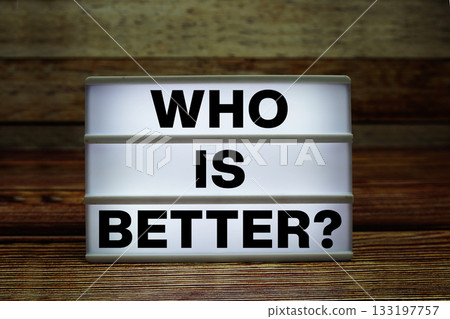 Lightbox with text "Who Is Better?" on wooden background Lightbox with text "Who Is Better?" on wooden background 133197757