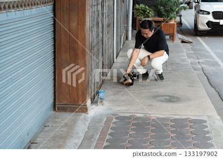 Small Encounters, he stops for a moment to pet a stray cat reminding that small connections can bring unexpected joy and meaning. Small Encounters, he stops for a moment to pet a stray cat reminding that small connections can bring unexpected joy and meaning. 133197902