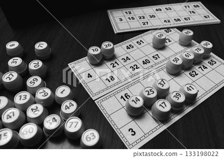 Playing lotto game, monochrome. Dices with figure on bingo card background, black and white. Nostalgia lifestyle. Table games. Retro games. Barrel with number and paper cards for bingo game.  133198022
