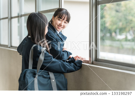 Junior high school girls in uniforms talking in the school corridor Junior high school girls in uniforms talking in the school corridor 133198297