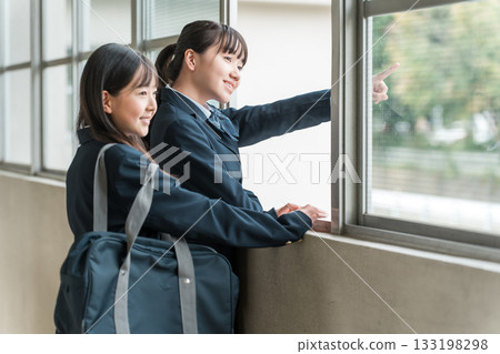 Junior high school girls in uniforms talking in the school corridor 133198298