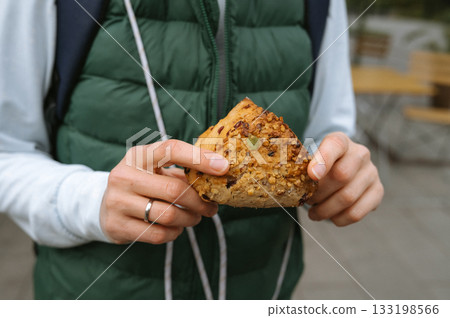 Caucasian young adult holding a nutty pastry outdoors 133198566