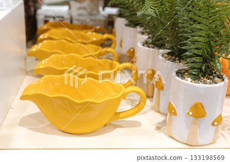 Yellow leaf-shaped dishes and mushroom planters in a decorative display 133198569