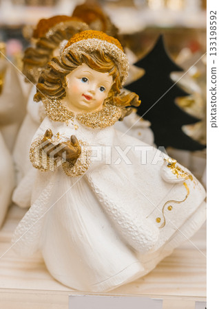 Elegant ceramic angel figurine with golden accents in winter attire Elegant ceramic angel figurine with golden accents in winter attire 133198592