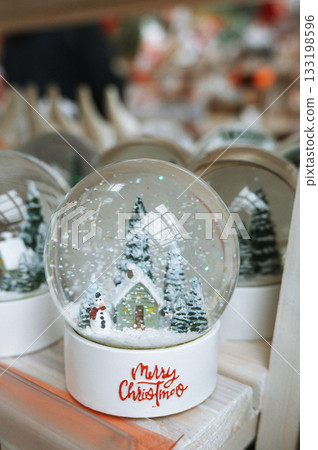 Festive holiday snow globe with cottage and snowman scene 133198596