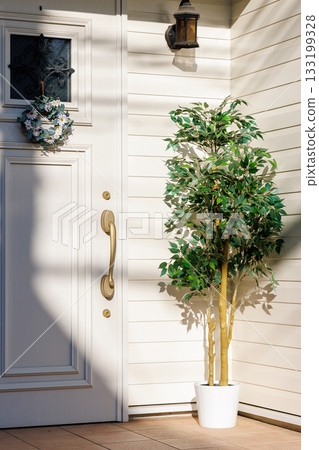 白色木板牆的房子裡，前門和綠植相映成趣。 133199328
