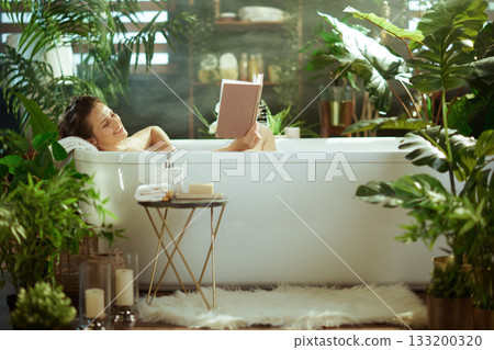 Happy Woman Enjoys Reading in Her Bathtub 133200320