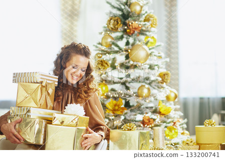 Woman Holding Many Gold Christmas Gifts Woman Holding Many Gold Christmas Gifts 133200741