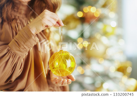 Elegant Woman Displays Gold Christmas Ornament Elegant Woman Displays Gold Christmas Ornament 133200745