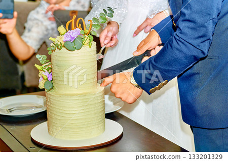 Elegant groom in blue suit cutting wedding cake 133201329