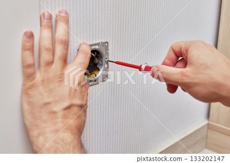 male hands installing electrical wall outlets with a screwdriver at home male hands installing electrical wall outlets with a screwdriver at home 133202147