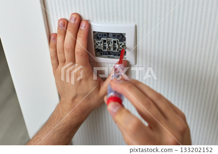 electrician installing electric light switch using screwdriver at home, close-up electrician installing electric light switch using screwdriver at home, close-up 133202152