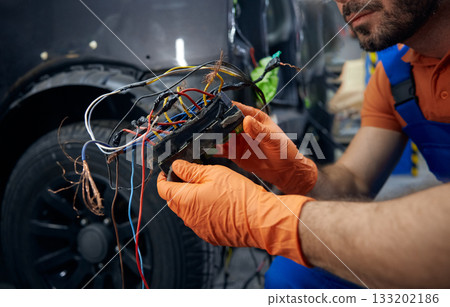 Mechanic inspecting complex car wiring harness in garage Mechanic inspecting complex car wiring harness in garage 133202186