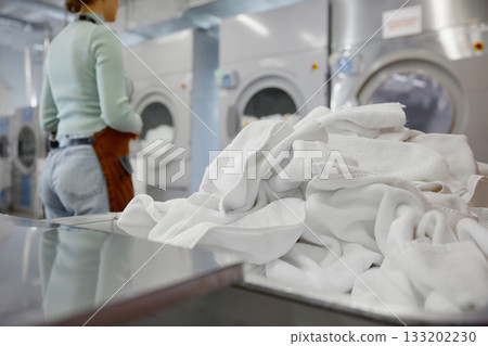 Freshly washed white towels are neatly piled on a laundromat counter 133202230