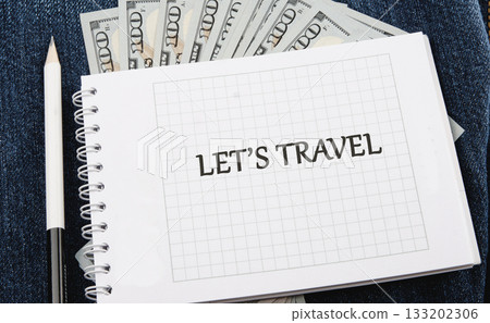 Cash money, white pencil, and a notepad that reads LETS TRAVEL are arranged on blue denim. Someone is planning a trip and budgeting for an upcoming adventure Cash money, white pencil, and a notepad that reads LETS TRAVEL are arranged on blue denim. Someone is planning a trip and budgeting for an upcoming adventure 133202306