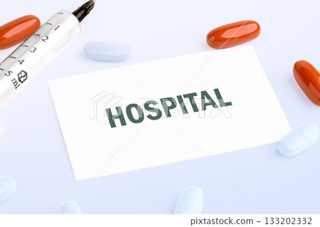 Medical treatment idea with a syringe, red and white pills, and a note with the word Hospital on a white background, suggesting care and medication Medical treatment idea with a syringe, red and white pills, and a note with the word Hospital on a white background, suggesting care and medication 133202332