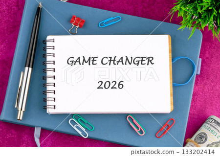 A planner sits on a desk with a note saying GAME CHANGER 2026. A pen, paper clips, money, and green plant are displayed, hinting at strategic planning for future achievements A planner sits on a desk with a note saying GAME CHANGER 2026. A pen, paper clips, money, and green plant are displayed, hinting at strategic planning for future achievements 133202414