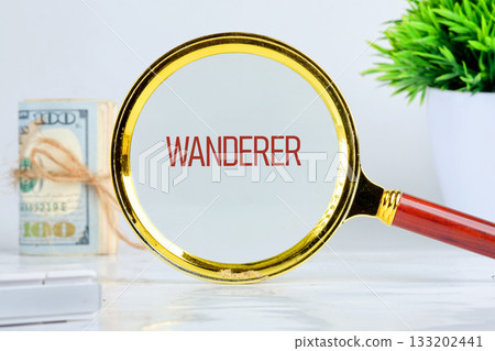 A magnifying glass reveals the word Wanderer. Stack of one hundred dollar bills secured with twine rests nearby, with a plant in the background, suggesting a focus on financial independence A magnifying glass reveals the word Wanderer. Stack of one hundred dollar bills secured with twine rests nearby, with a plant in the background, suggesting a focus on financial independence 133202441