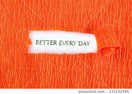 Against a vivid orange background, a piece of paper peeks through, revealing the uplifting message of better every day. This design encourages continuous self-improvement Against a vivid orange background, a piece of paper peeks through, revealing the uplifting message of better every day. This design encourages continuous self-improvement 133202494