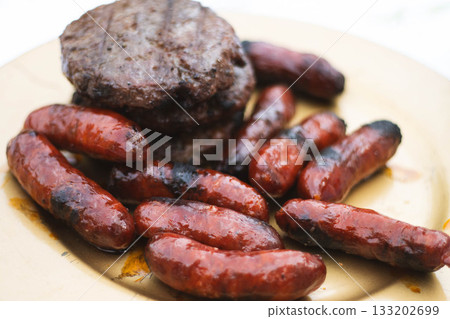 Grilled chorizos and hamburgers served on rustic plate 133202699