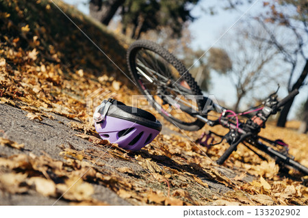 Purple helmet lies abandoned on the pavement beside a toppled bicycle, evidence of a sudden fall. 133202902