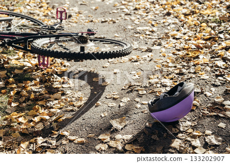 Purple helmet lies abandoned on the pavement beside a toppled bicycle, evidence of a sudden fall. 133202907