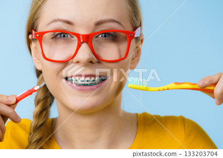 Woman smiling cleaning teeth with braces Woman smiling cleaning teeth with braces 133203704