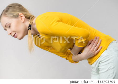 Woman feeling stomach cramps holding her belly Woman feeling stomach cramps holding her belly 133203705