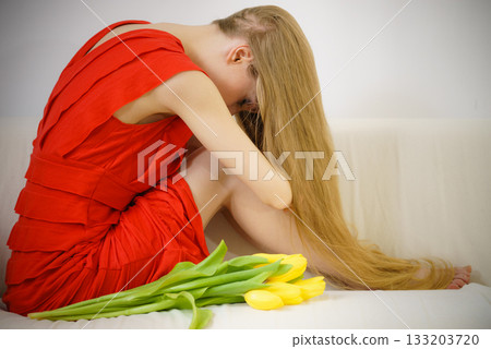 Sad elegant woman sitting on sofa with tulip Sad elegant woman sitting on sofa with tulip 133203720