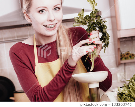 Woman in kitchen making vegetable smoothie juice 133203745