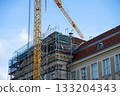 Scaffolding with a tall yellow crane and metal scaffolding during renovation work on a historic building. Equipment for construction workers 133204343