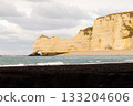 Limestone sea cliffs and natural arch at Etretat, Normandy, framed by ocean waves and a calm coastal landscape. 133204606