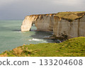 Etretat cliffs with natural sea arch on the Normandy coast, captured in warm sunlight. 133204608