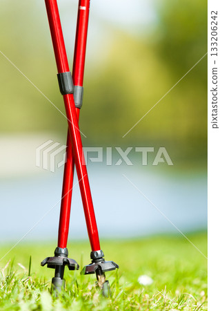 Nordic walking. Red sticks on grass in park 133206242