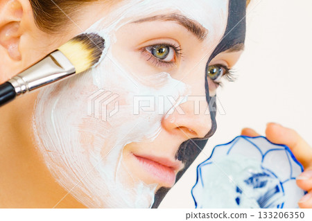 Girl black mask on half face apply white mud Girl black mask on half face apply white mud 133206350
