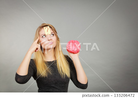 Woman thinking and holding fake brain 133206472