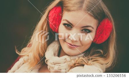 Portrait of pretty smiling woman in red earmuffs. 133206556