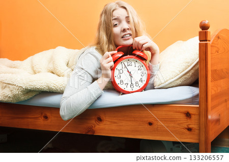 Unhappy woman waking up with alarm clock. 133206557