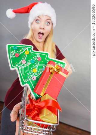 Santa woman holding shopping cart with christmas gifts Santa woman holding shopping cart with christmas gifts 133206590