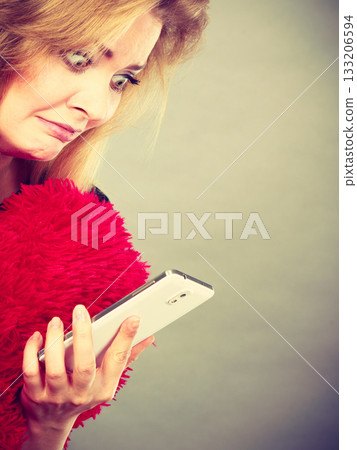 Shocked heartbroken woman looking at her phone 133206594