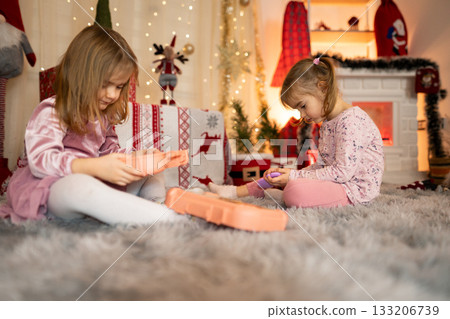 Two little girls playing with toys in a Christmas decorated living room Two little girls playing with toys in a Christmas decorated living room 133206739